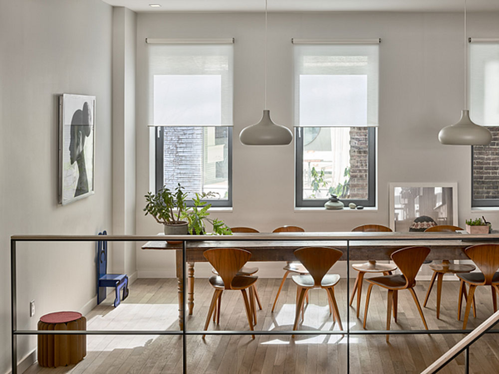 Motorized roller shades held at preset over a dining room — daylight controlled, view preserved